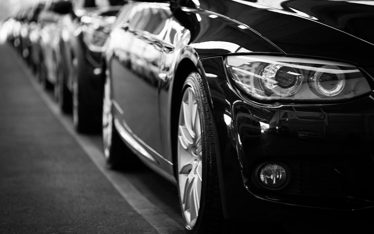 Home Close-up black and white image of a luxury car line-up focusing on vehicle headlights.